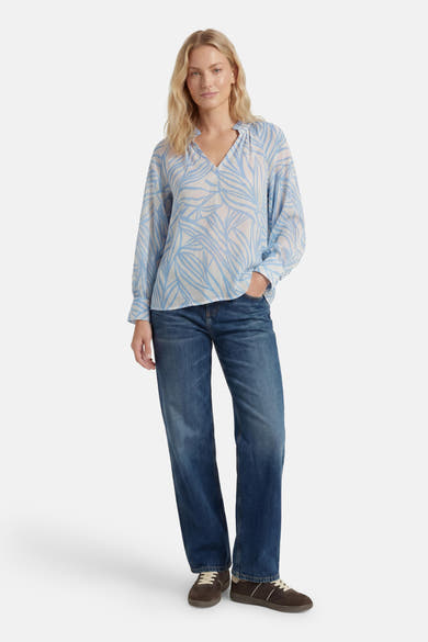 Chemisier à manches longues bleu clair et blanc de GOA GOA, à motif de feuilles et col en V, porté avec un jean.
