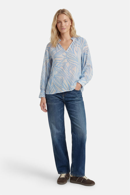 Chemisier à manches longues bleu clair et blanc de GOA GOA, à motif de feuilles et col en V, porté avec un jean.