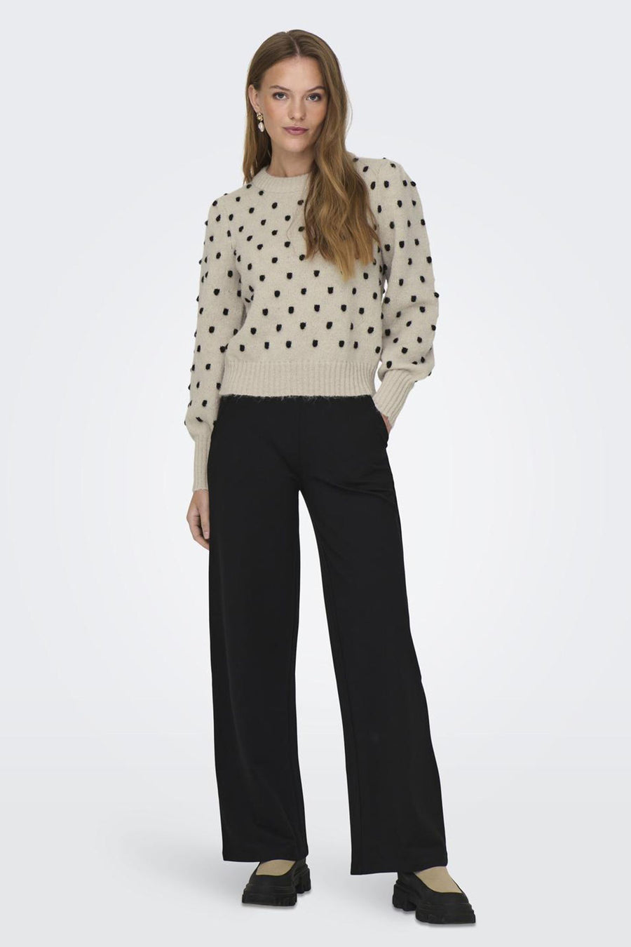 Rondkraagwit JDY JDJDY met, textururur texten, g drragen in een brede zwarte broek en zwarte laarzen met platte zolen.