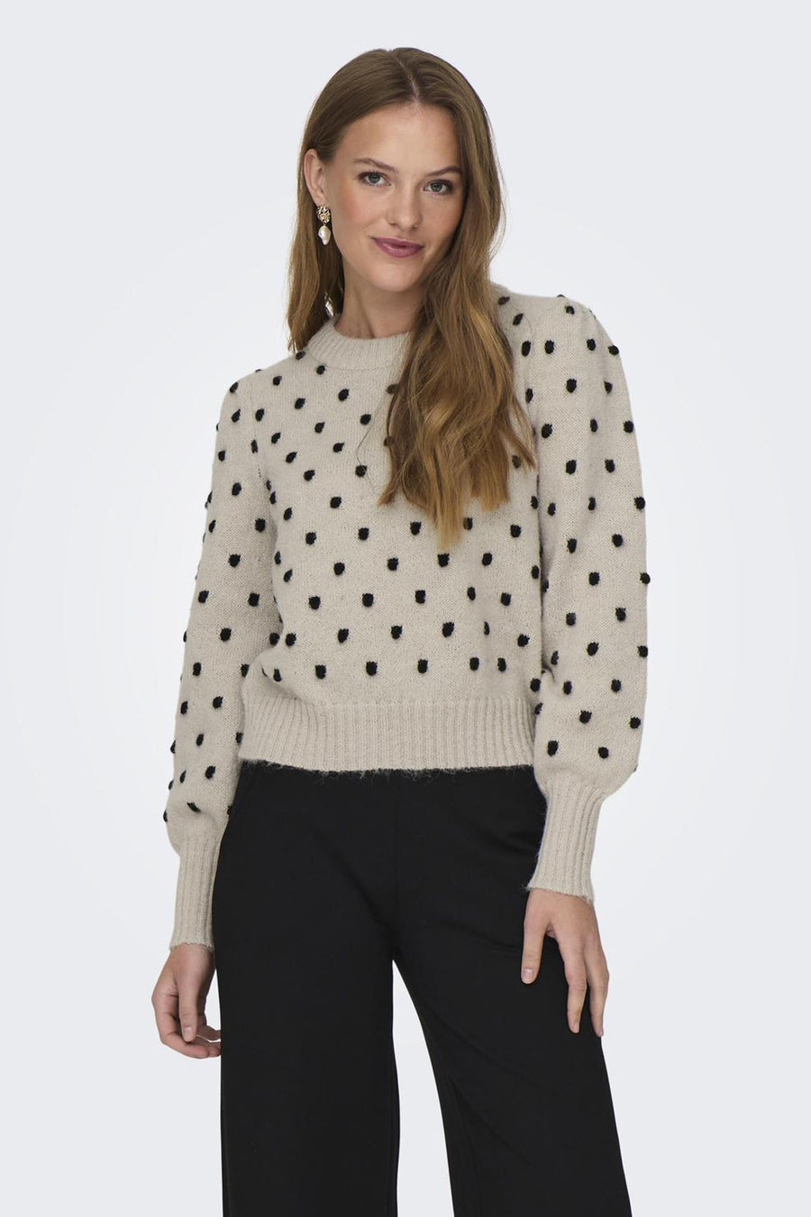 Ronde mouw van JDY in ecru met texturde zwarte stippen, gedragen met een zwart fluïd pantalon en hangers oorhangers.