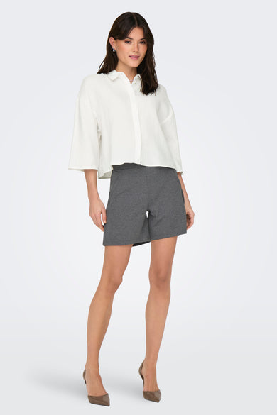 Wit chemisier met korte mouwen van JDY, gedragen met donkere shorts en hakken.