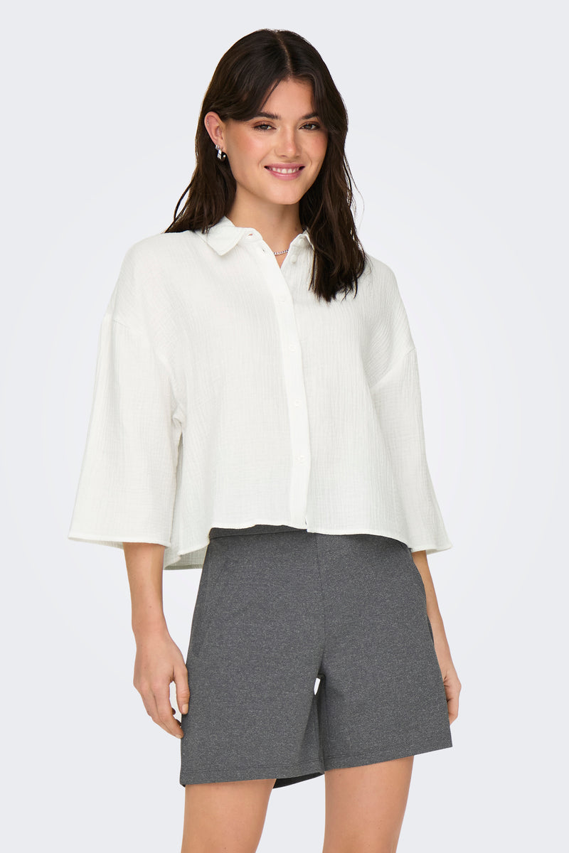 Witte blouse met korte mouwen van JDY, gedragen met een grijs broekje, op een lichte achtergrond.