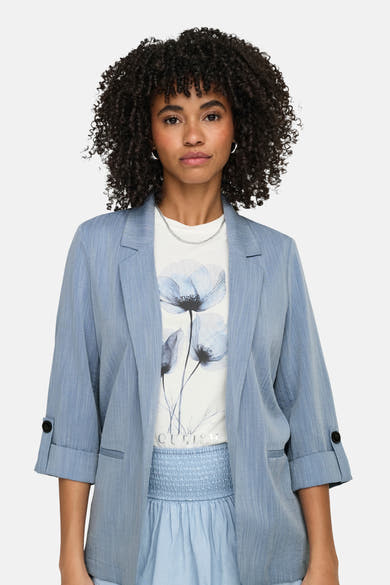Blauwe blazer van ONLY, met driekwartmouwen en knopen bij de manchetten, gedragen over een T-shirt met bloemenprint.