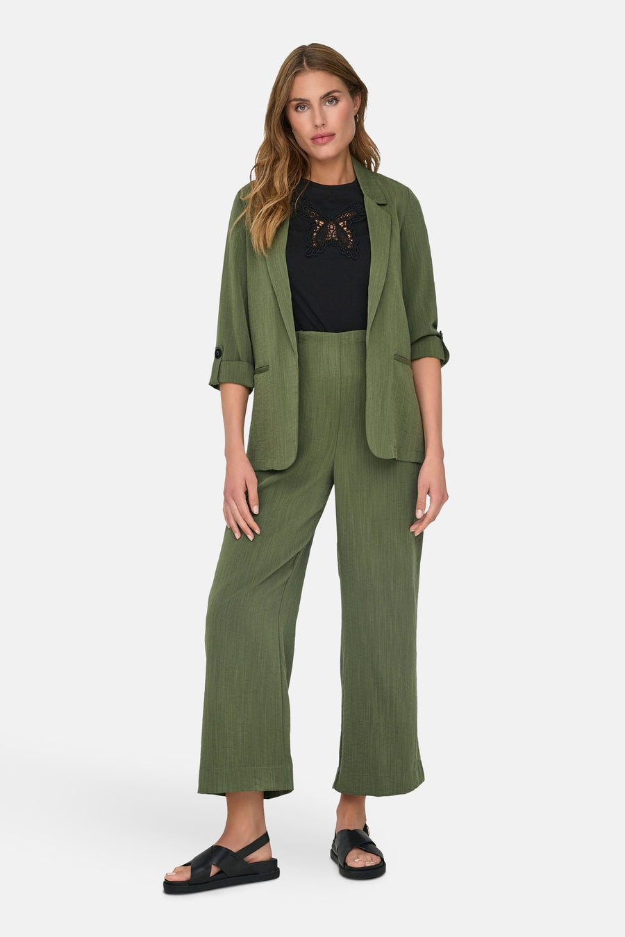 Blazer vert olive de ONLY, porté avec un pantalon assorti et un t-shirt noir à dentelle.