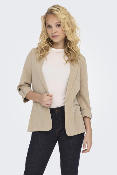 Blazer beige de ONLY, avec manches 3/4 retroussées porté sur un t-shirt clair et un jean foncé.