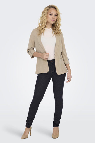 Blazer beige de ONLY®, avec des manches trois-quarts et porté par-dessus un t-shirt blanc et un jean bleu foncé.