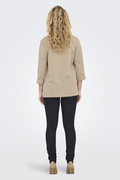 Blazer beige van ONLY, porté avec un jean foncé et des talons hauts couleur chair, vue de dos.
