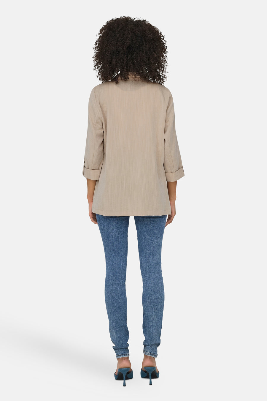 Blazer beige ONLY® à manches trois-quarts et revers retroussés, porté avec un jean moulant bleu et des mules à talons aiguilles.
