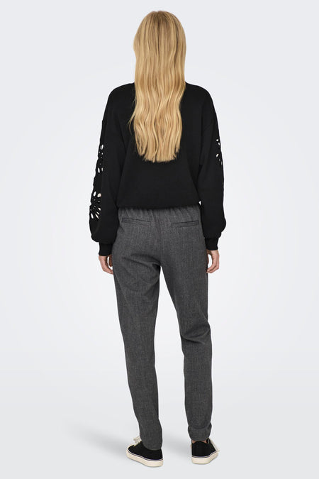 Pantalon gris chiné de ONLY, porté avec un pull noir à manches ajourées et des baskets à semelle blanche.