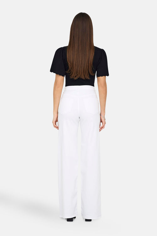 Jean large blanc de ONLY®, porté avec un haut noir et un bracelet argenté, vue de dos.
