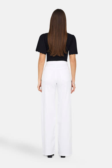 Jean large blanc de ONLY®, porté avec un haut noir et un bracelet argenté, vue de dos.
