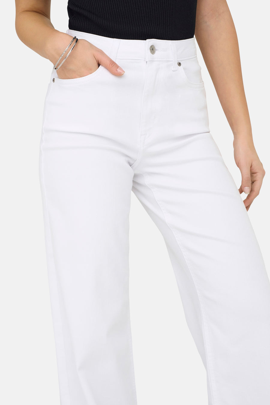 Jean large blanc de ONLY, avec une main dans la poche, porté avec un bracelet argenté.