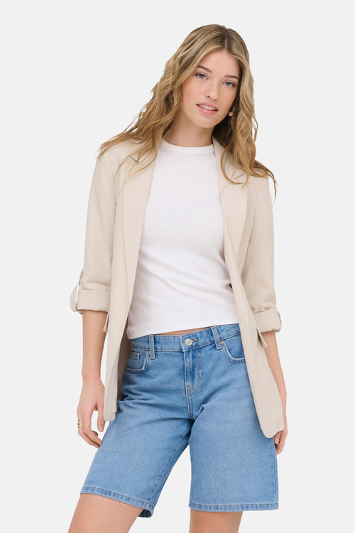 Blazer beige de ONLY, porté avec un t-shirt blanc et un short en jean.
