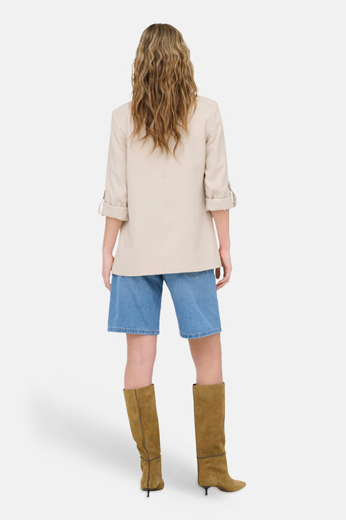 Blazer beige de ONLY®, porté avec un short en jean et des bottes hautes marron, vue de dos.