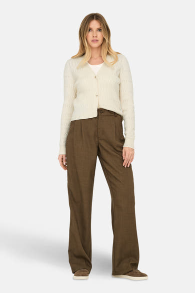 Cardigan beige en maille par ONLY®, porté avec un pantalon marron taille haute et des chaussures de sport.
