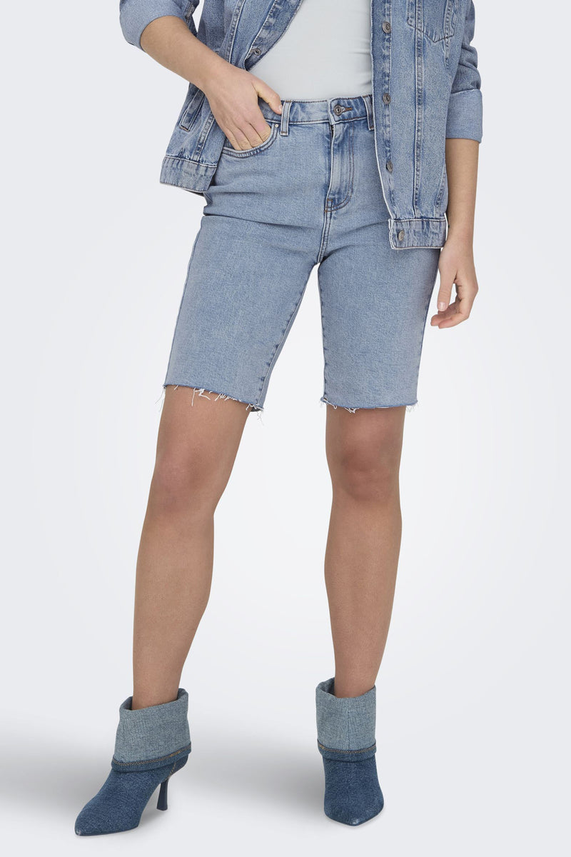 Bermuda court bleu de ONLY, porté avec une veste en jean et des escarpins assortis.