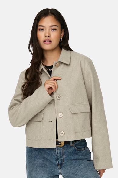 Veste courte beige de JDY, avec boutons, poches plaquées et porté sur un jean taille haute.
