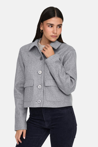 Korte grijze jas van JDY met klepzakken en zilveren knoopsluiting, gedragen met een corduroy broek.