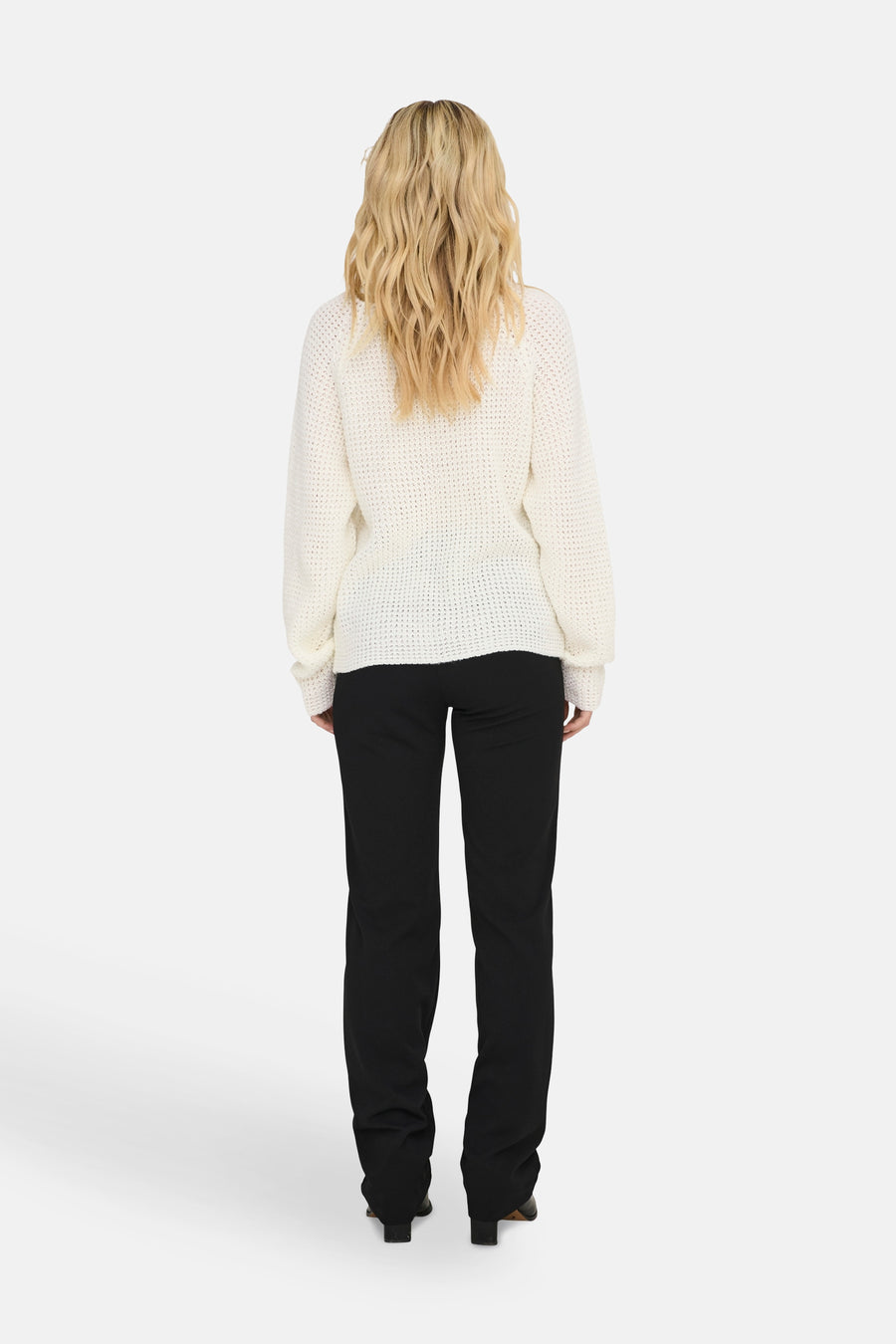 Pull à col rond blanc de JDY, en maille texturée, porté avec un pantalon noir.
