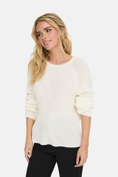 Pull à col rond blanc de JDY, en maille ajourée, porté avec un pantalon noir.
