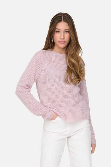 Roze rondehals trui van JDY, in opengebreid breisel gedragen met een witte broek.