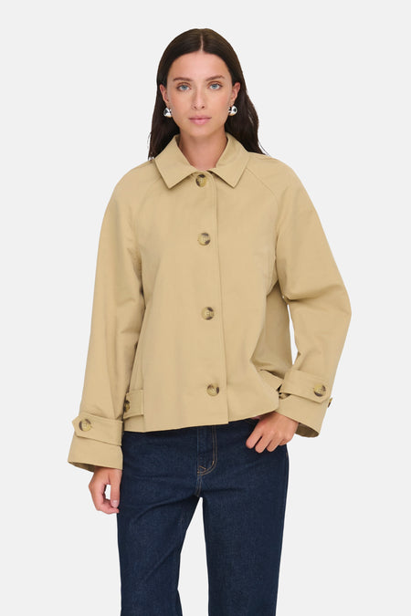 Veste courte beige de JDY avec une rangée de boutons ton sur ton, portée avec un jean bleu.
