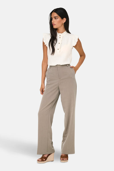 Pantalon de costume beige de ONLY, porté avec un haut blanc à volants et des sandales compensées.
