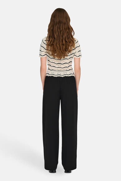 T-shirt écru à rayures noires de ONLY, porté avec un pantalon noir ample.
