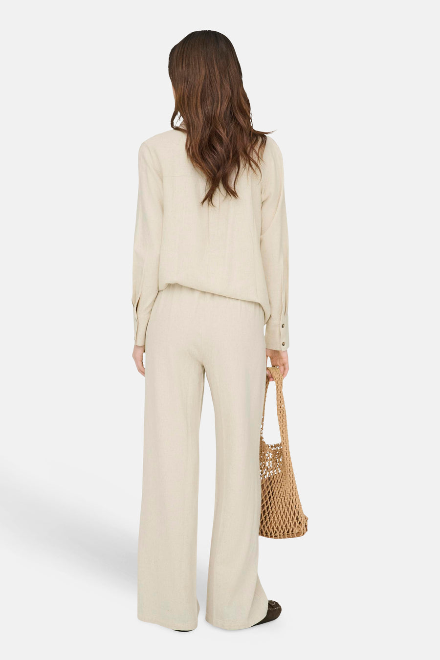 Beige broek met wijde pijpen van JDY in een getextureerde stof, van achteren gedragen met een bijpassend overhemd en een nettas.
