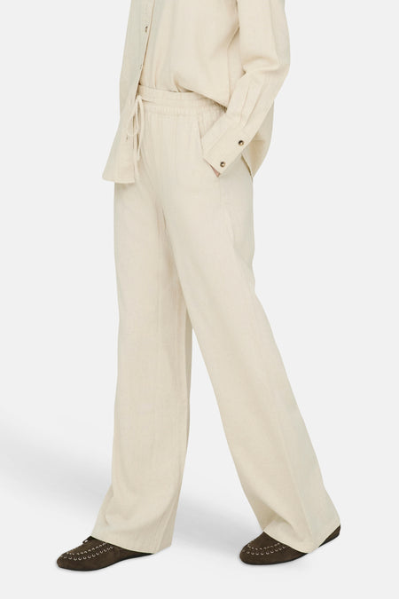Beige wijde broek van JDY, elastische tailleband met trekkoord en zakken, gedragen met donkere loafers.