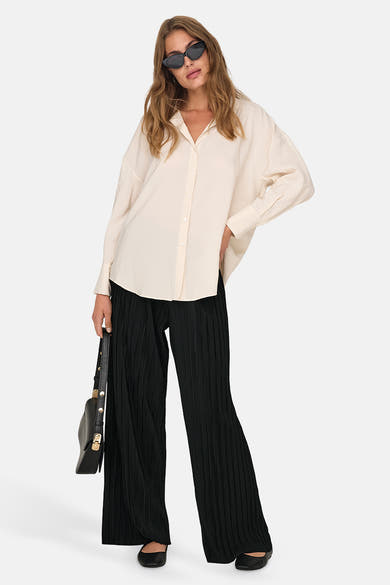 Zwarte kleurrijke broek van ONLY, met een geplooide textuur en losse pasvorm, gedragen met een zwarte blouse en handtas.