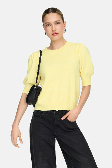 Pull à col rond jaune de ONLY®, manches bouffantes, porté avec un jean noir et un sac à main noir.
