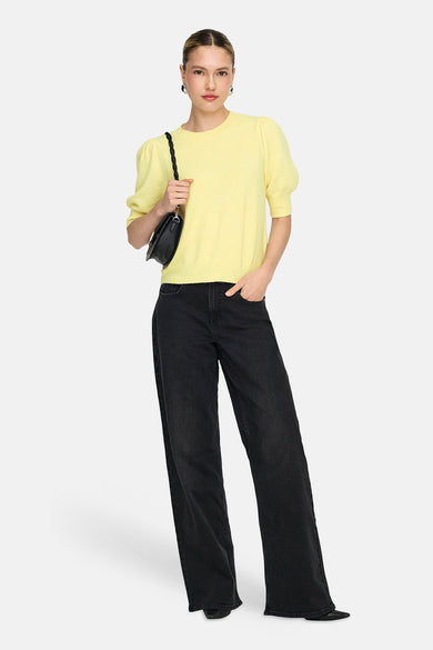 Pull jaune à col rond de ONLY®, porté avec un jean noir ample et un sac à main noir.
