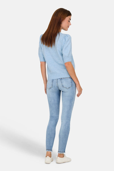 Ronde hals trui in lichtblauw van ONLY®, korte pofmouwen, gedragen met een spijkerbroek en witte sneakers.