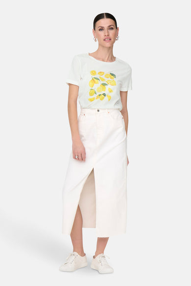 T-shirt à manches courtes blanc de JDY avec motif citron, porté avec une jupe blanche et des baskets blanches.
