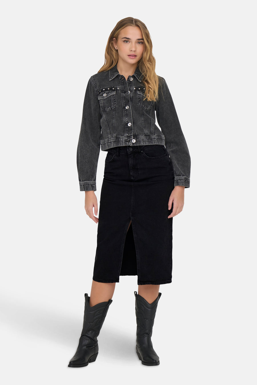 Zwarte midi-rok met split van ONLY, gedragen met een verweerd spijkerjack en zwarte cowboylaarzen.