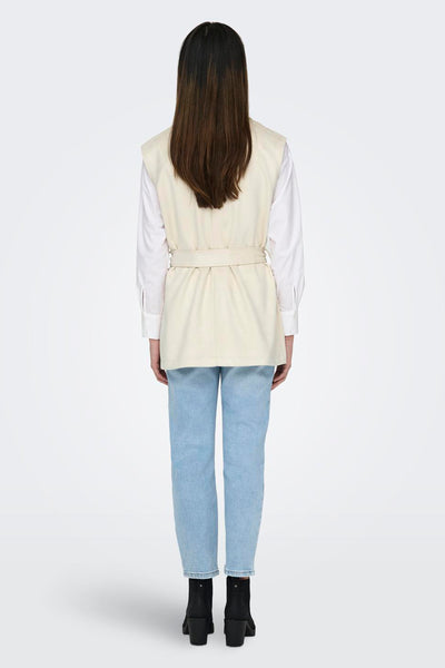 Beige jas van ONLY, gedragen met een wit overhemd met lange mouwen en een lichtblauwe jeans.