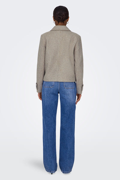 Veste courte beige de ONLY, avec un col tailleur et des manches longues, portée avec un jean bleu taille haute.