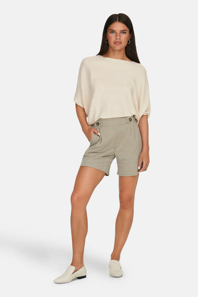 Short beige de JDY, avec taille haute à boutons et poches avant, porté avec un pull crème et des mocassins blancs.