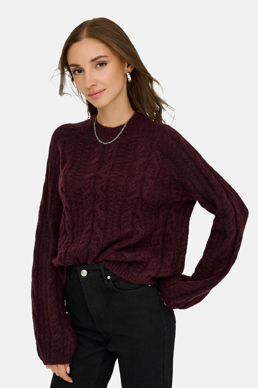 Bordeauxrode coltrui van JDY met een kabelpatroon, gedragen met een zwarte jeans en een zilveren ketting.