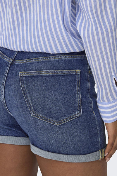 Medium blue denim shorts with rolled cuffs and back pocket, worn with a blue and white striped top, side view close-up