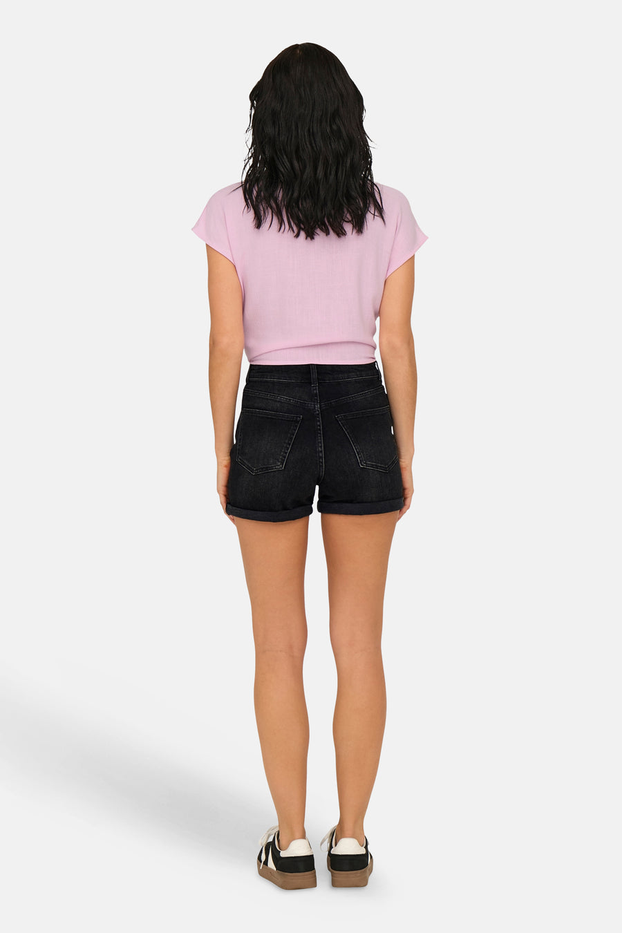 Short en jean noir de ONLY® à taille haute et ourlets retroussés, porté de dos par une femme.