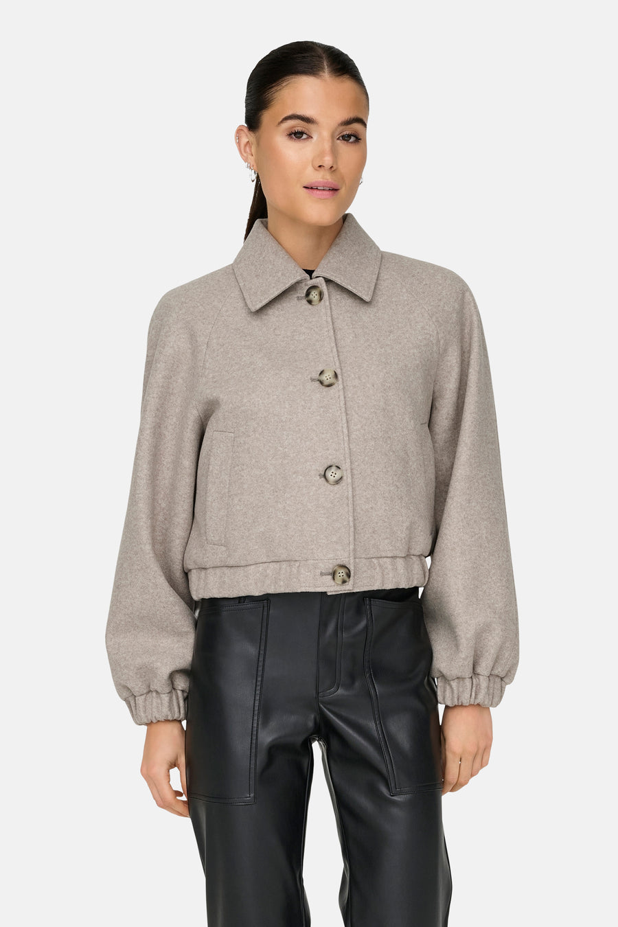 Veste courte beige de ONLY, avec col classique et boutons, portée avec un pantalon en cuir noir.
