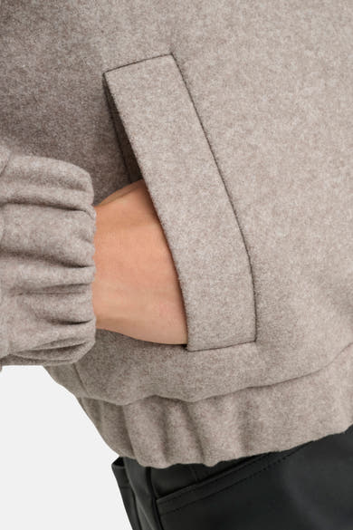 Veste courte beige de ONLY, avec une main dans la poche, et manches resserrées.