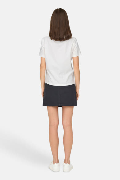 T-shirt blanc à manches courtes de JDY, porté avec une jupe noire et des baskets blanches, vue de dos.
