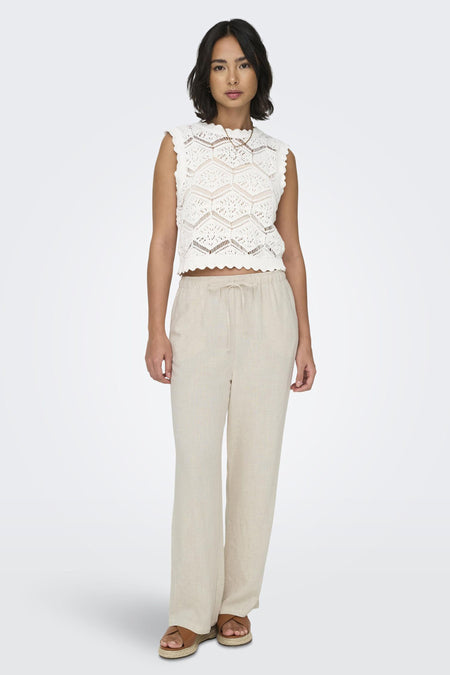 Pantalon écru de ONLY, ample avec cordon de serrage, porté avec un haut en crochet blanc et des sandales compensées.
