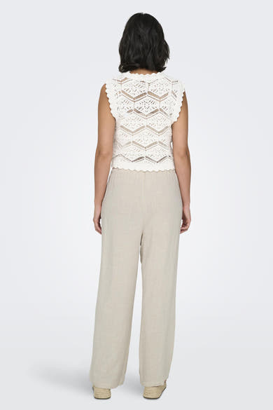Witte broek van ONLY, ruim en vloeiend, gedragen met een gecrochetteerd textuurtop en espadrilles.