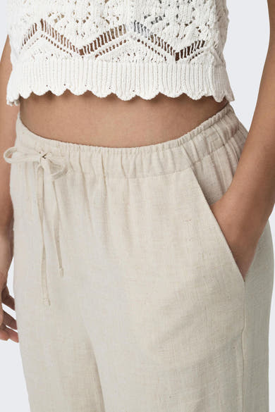 Witte broek van ONLY®, met een knoopsgordel en poche, gedragen met een haakjesboven.