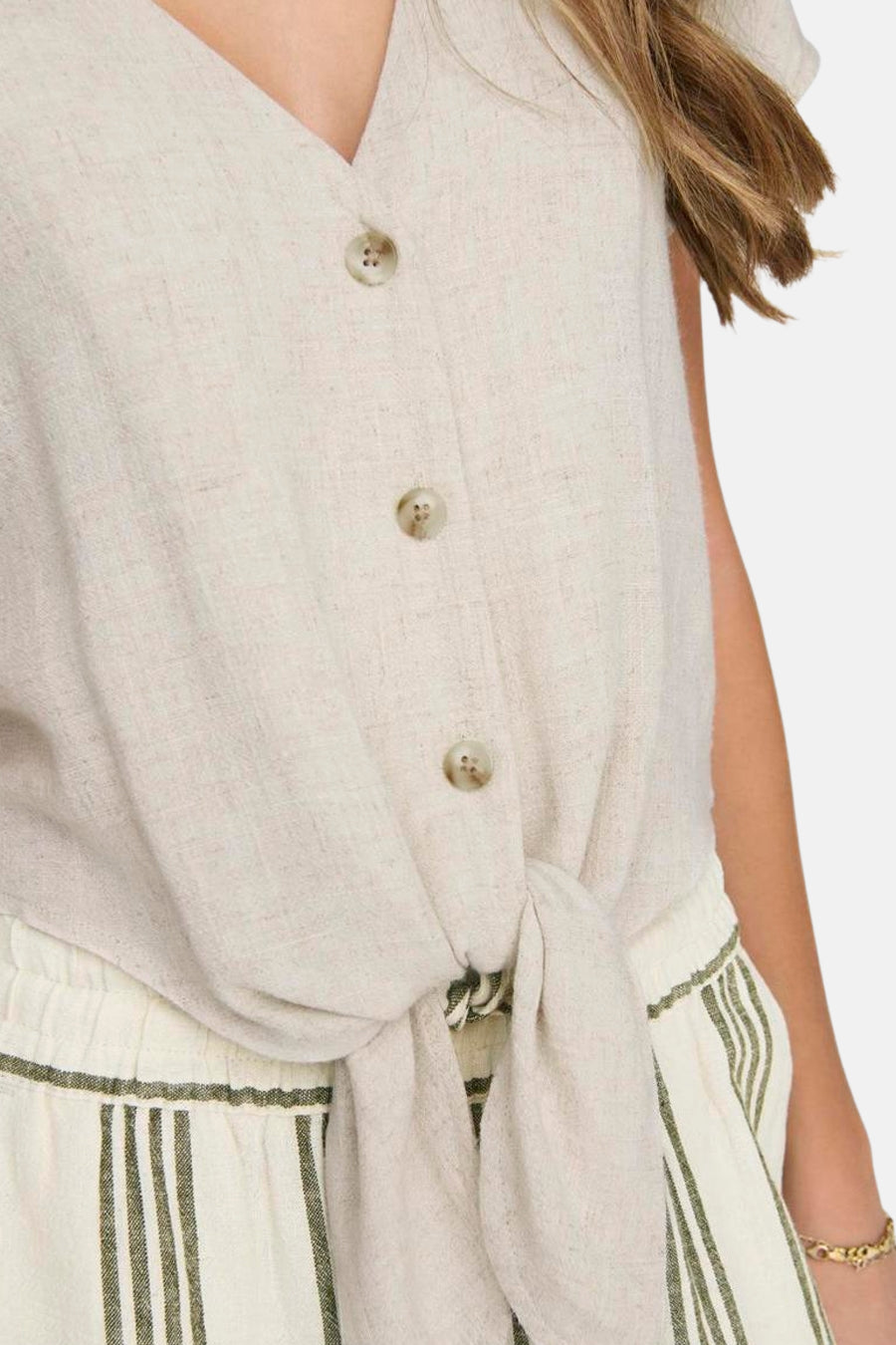 Beige blouse met korte mouwen van ONLY, met knopen en een strik aan de voorkant, gedragen met een gestreepte broek.