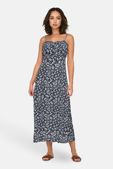 Robe midi bleue à motif floral blanc de ONLY® portée par une femme avec des sandales marron.